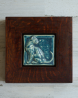 The 3D Cat Tile features a sleek cat sitting up straight with its head turned backward towards its flicking tail. The tile is in the matte french blue Peacock glaze which beautifully offsets the deep reddish brown of the oak wood frame.