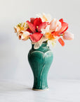 A Pewabic Green-glazed, Small Classic Vase dressed with pink tulips, and neutral daffodils against an ivory backdrop.