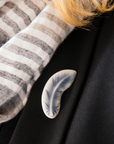 The Feather Pin is a small, light design. The feather is gently curved with straight barbs at the top and softer, wispier barbs near the bottom.