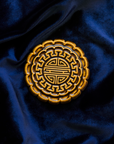 A Mooncake Paperweight in our glossy Molasses glaze on a rich, blue velvet.