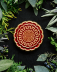 A Mooncake Paperweight in two-tone Scarlet/Honey surrounded by cool greenery and delicate concord grapes.