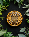 A Mooncake Paperweight in our glossy Molasses glaze, surrounded by cool greenery and delicate concord grapes.