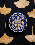 A Mooncake Paperweight in two-tone Lapis/Scrape surrounded by dried ginkgo leaves.