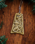The bell-shaped Five Gold Rings Ornament features five intertwined smooth rings. There are springs of holly leaves and berries throughout the design. The ornament is glazed in a matte yellow glaze.