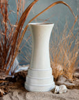 This Birch Step Vase sits in a diorama-like setting. Sand, rocks and brown grasses surround the vase, reminiscent of a Michigan day at the dunes.