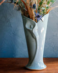 The calla lily vase fits a medium to large bouquet. The sides of the sleek vase start small at the base and slope out to create a large opening at the top. A high relief shape of a calla lily flower is front and center creating a modern, elegant look.