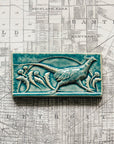 This hand-sculpted tile features a pheasant running through a field of dandelions. It is featured in a glossy blue Glacier glaze.