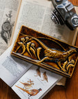 The long, horizontal Pheasant Tile features a male ring-necked pheasant running across the tiles. Puffy late-summer dandelions surround its outstretched feet. A large, domed sun is setting behind it. Featured in in a glossy brown Molasses glaze.