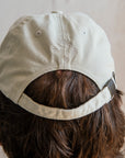 The back of the off-white hat features the Pewabic logo and adjustable fabric strap.