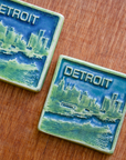 This two-tone Detroit Skyline tile is featured in the Lime/Lagoon color palette. The sky and water are in the matte blue Lagoon glaze and the skyline, boat, and word is in the matte bright light green Lime glaze.