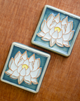 The Lotus tile features a line drawing of a blooming lotus flower, its pointed petals outstretching. It has a simple border around the design.