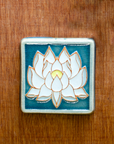 This Hand-painted Lotus Tile features white petals and a yellow center on the flower which sits on a deep blue background.