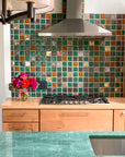 Multicolored tile backsplash in a kitchen with modern cabinets and a jade green countertop