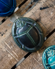 This paperweight features the satin-finished steel black Gun Metal Glaze. In parts where the glaze is thinner - on the edges of the design - the glaze has a mottled green color.