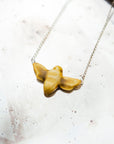 The matte Mustard colored bee pendant is attached to a silver chain.
