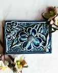 The Dogwood Tile features a blooming branch from a Dogwood tree- the three large flowers have four petals each with a bumpy circular center.