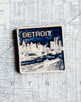 The Detroit Skyline tile features the current downtown skyline with the Detroit River in the foreground. A freighter floats by causing ripples on the otherwise flat surface of the water. The word "Detroit" is written above in the sky. This tile is in the two tone Midnight/Scrape option. The sky and water are in the glossy deep dark blue Midnight glaze while the skyline, boat and word is scraped to make a creamy white color.