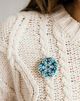 This delicate Snowflake Pin is a hexagonal shape. Six frosted tines break out from the snowflake's center. The pin in glaze in a glossy blue color that is almost white on the raised snowflake design and pools to a deep color on the background.