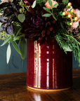 A close-up of a flower-filled crock details the glossy, deep red Winterberry glaze.