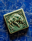 The Taurus tile in emerald glaze sits on a vintage blue and white map of the celestial sky.