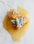 The glossy blue Glacier Gloss glazed bee pendant is attached to a silver chain.
