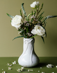 The Snowdrop vase has a wide, round base that contracts into a pillar as it gets taller. The rim of the vase has small snowdrop flowers whose stems glide gracefully down the sides of the vase.