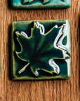 The kale glazed maple leaf tile is featured. This tile is a deep glossy green.