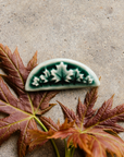 This Maple Leaf Pin is shaped like a half circle. It features five maple leaves in a fan-like formation with the largest in the center and smaller leaves flanking it at the sides.