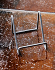 Detail photo of the matte silver stand. It is empty and on a tiled-window ledge.