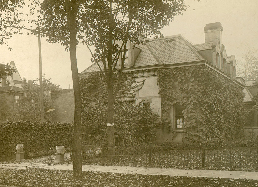 A historic image of the Stable Studio; a stucco building with ivy crawling up its walls and surrounded by trees.