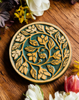 The round Ivy Trivet features a long branch of leafy ivy that curves into a spiral that ends in the center of the trivet.
