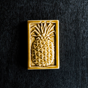 This high relief rectangular tile features a large pineapple with textured sides and spiky fronds. This tile has a plain border and comes in the deep golden Honey Gloss glaze.
