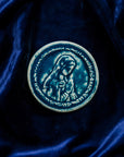 This ceramic Blessed Virgin Mary Tile is glazed in a French-blue, matte Peacock glaze resting on a bed of rich, blue velvet.