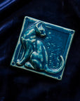 This cat tile is shown in a matte-blue Peacock glaze resting on a bed of rich, blue velvet.