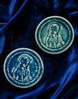 These ceramic Blessed Virgin Mary Tile are glazed in a pale blue, glossy Glacier glaze and French-blue Peacock glaze. They are resting on a bed of rich, blue velvet.