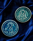 These ceramic Blessed Virgin Mary Tile are glazed in a pale blue, glossy Glacier glaze and French-blue Peacock glaze. They are resting on a bed of rich, blue velvet.