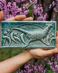 This hand-sculpted tile features a pheasant running through a field of dandelions. It is featured in a glossy blue Glacier glaze.