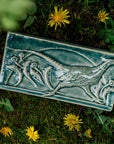 This hand-sculpted tile features a pheasant running through a field of dandelions. It is featured in a glossy blue Glacier glaze.