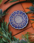 A Mooncake Paperweight in two-tone Lapis/Scrape surrounded by thistle and wax flowers.