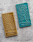 The Pewabic Blue and Honey glazed tiles lay next to each other on a black and white street map of Detroit.
