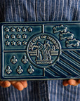 Hands hold the Detroit Flag Tile.