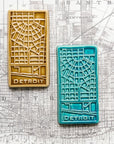This rectangular Detroit Map Tile has a line drawing of the areal street view of downtown Detroit. The word "Detroit" is written at the bottom of the design.