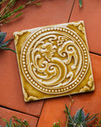 Thistles and greenery surround this Honey Phoenix Tile.