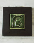 The Spartan Tile features a high relief design of a Spartan helmet with a large crest. This tile has the glossy deep green Kale glaze and sits in a black painted wood frame.