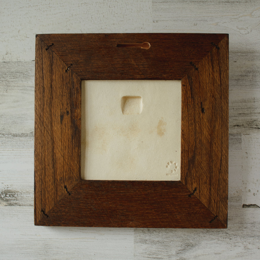 The back of the framed piece shows the open-back structure of the frame. This exposes the Pewabic Stamp on the back of the tile. 