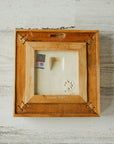 The back of the framed piece shows the open-back structure of the frame. This exposes the Pewabic Stamp on the back of the tile as well as the holographic licensing sticker.