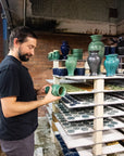 Kiln technician Brett inspects a Small Classic Vase in Pewabic Green glaze that just came out of Pewabic's large Blaauw Kiln