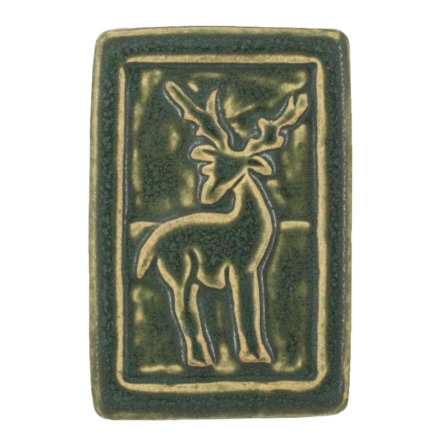The ceramic Deer Tile features a stag with its body in profile - but its head is turned to the viewer, showing off its large antlers. There is a thick border around the design. The entire tile is featured in our matte dark mossy green Bayleaf glaze.