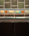 Details of the custom Iridescent glazed trim surrounding the opening of the fireplace. The metallic surface of these tiles stands out against the subdued bayleaf glaze.