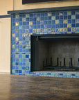 A blue iridescent tiled fireplace with accent tile around the center and custom-cut tile radiating from the center of the design.